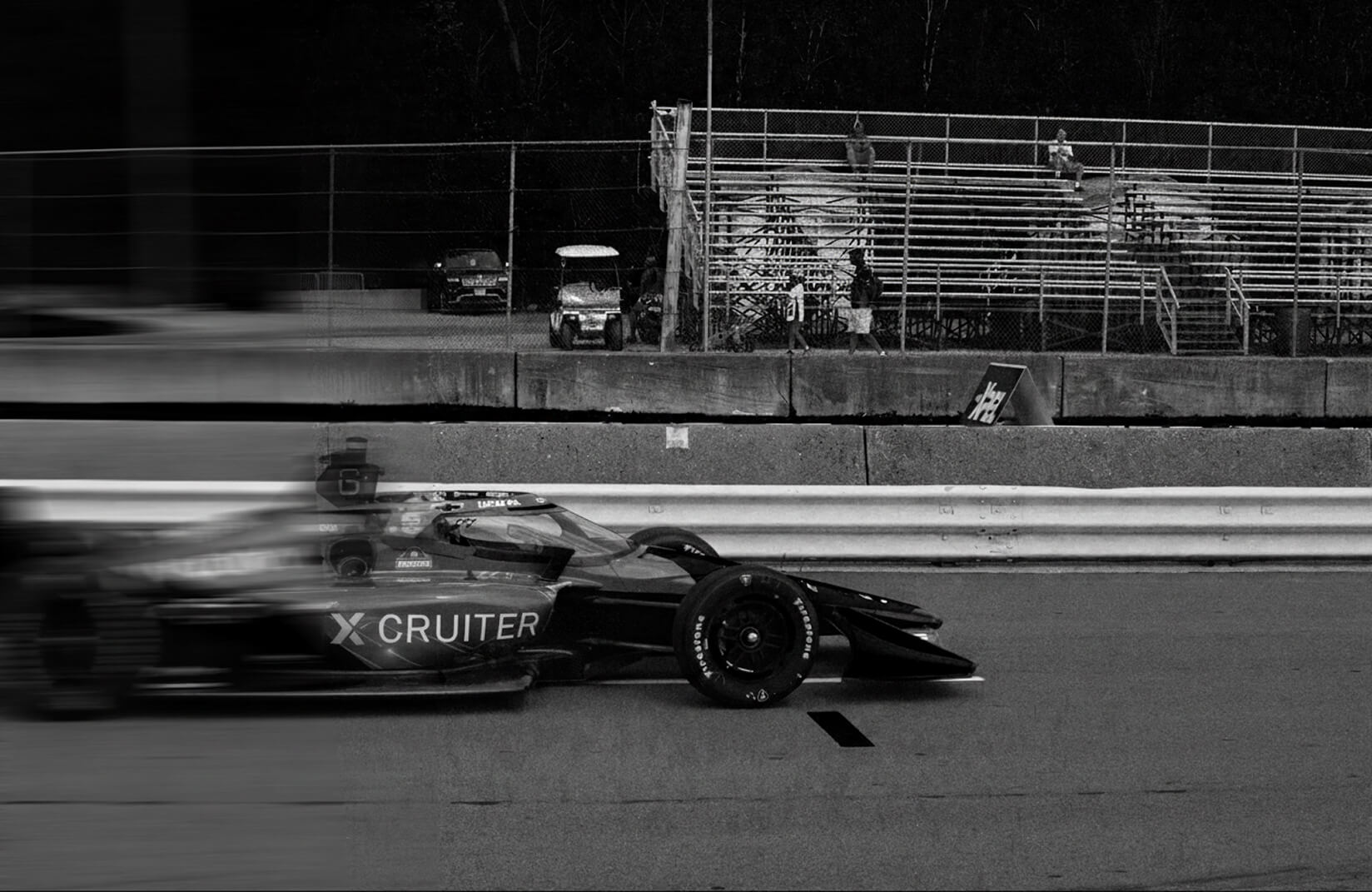 A Formula 1 car speeding past a racetrack grandstand.